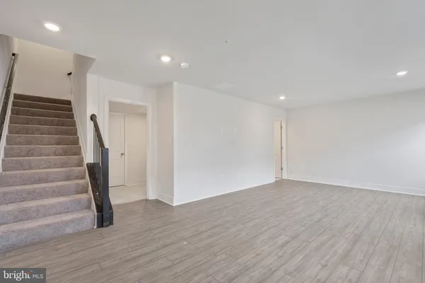 a view of an empty room with wooden floor and stairs