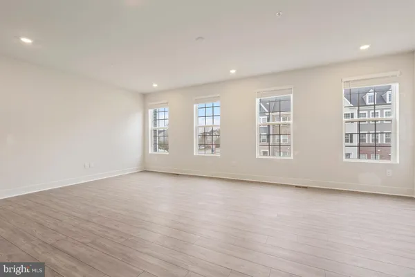 a view of an empty room with wooden floor and windows