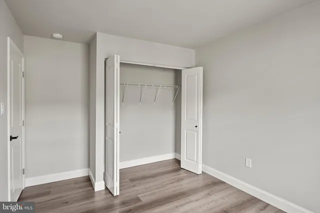 an empty room with wooden floor & closet area