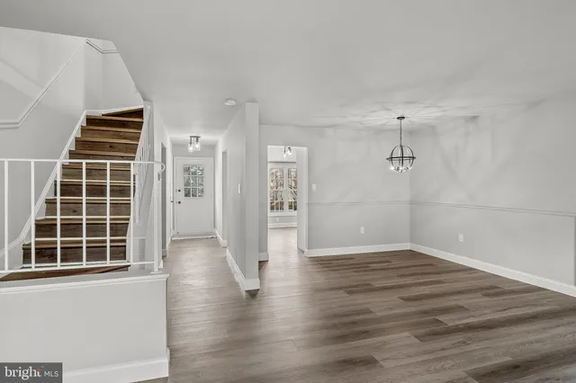 a view of an empty room with wooden floor and windows