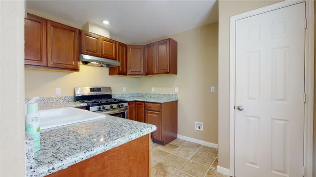 a kitchen with granite countertop a sink a stove and cabinets