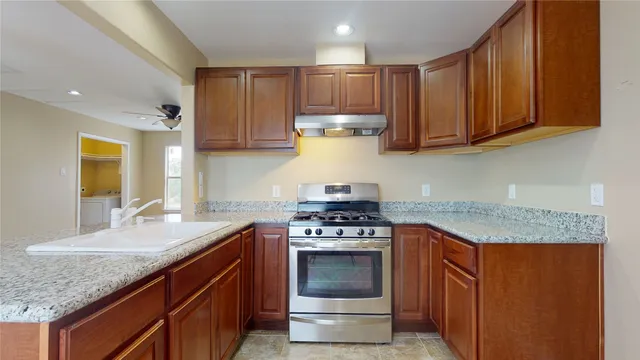 a kitchen with stainless steel appliances granite countertop wooden cabinets and granite counter tops