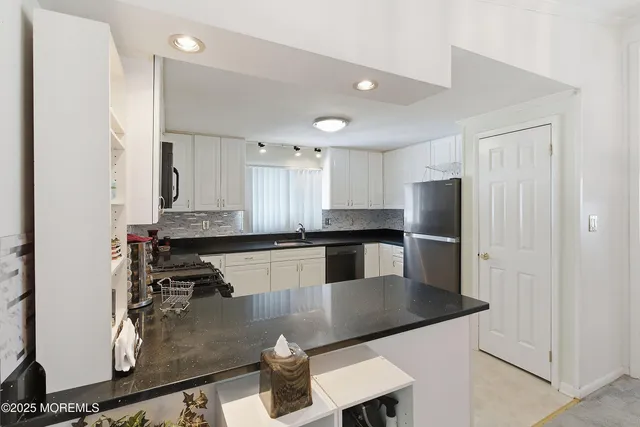 a kitchen with stainless steel appliances granite countertop a sink refrigerator and cabinets