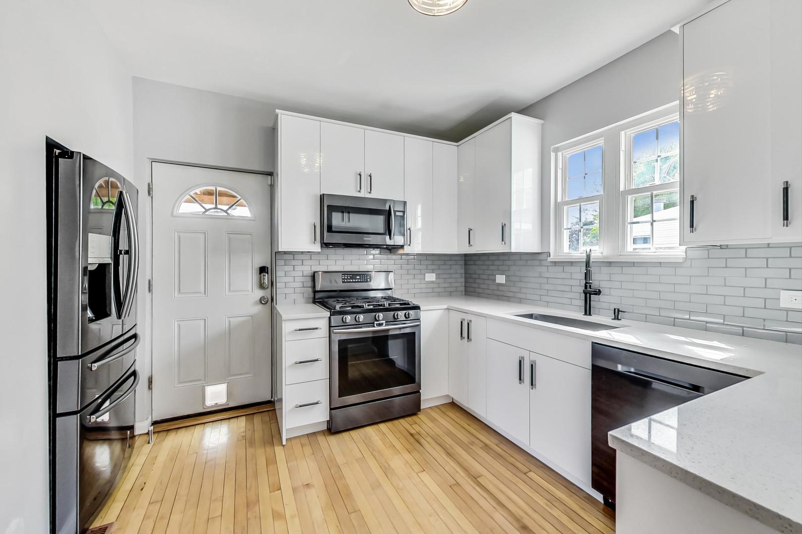 4015 West Addison Street Chicago, IL 60641 - Photo 5 of 30 a kitchen with stainless steel appliances a sink cabinets and a wooden floor
