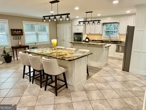 a room with stainless steel appliances kitchen island granite countertop a sink and a refrigerator