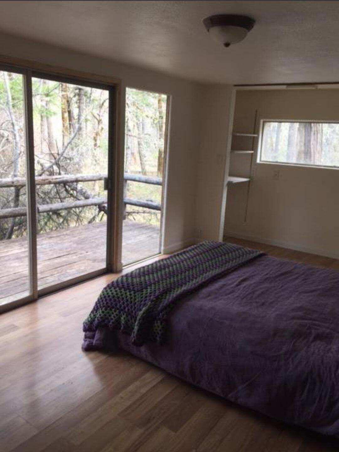 12100 Takilma Road Cave Junction, OR 97523 - Photo 14 of 20 a bed sitting in a bedroom next to a window