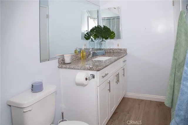 a bathroom with a granite countertop sink a toilet and a mirror