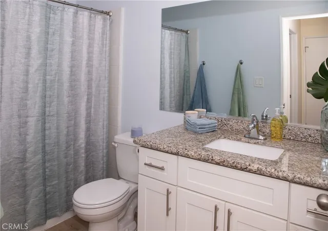a bathroom with a granite countertop sink and a toilet