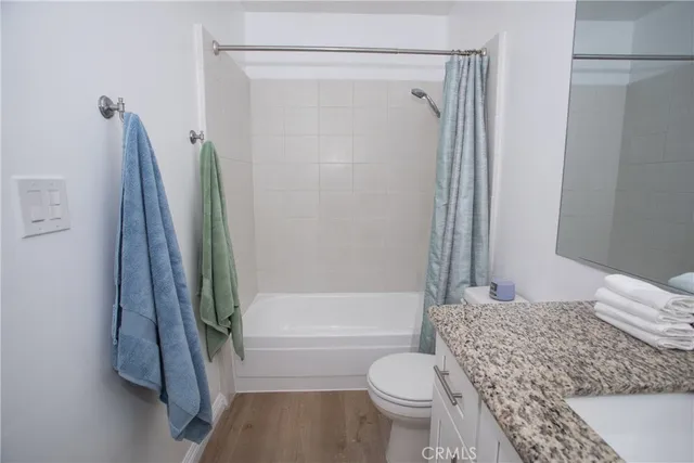 a bathroom with a granite countertop bathtub shower and a toilet