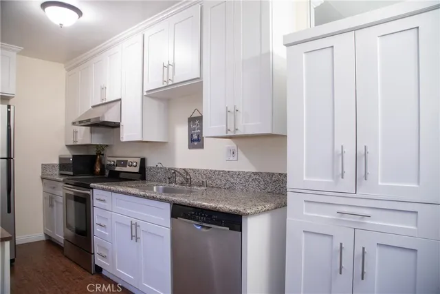 a kitchen with granite countertop white cabinets and a stainless steel appliances