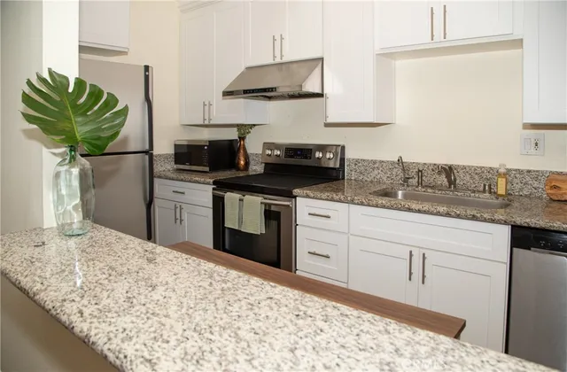 a kitchen with stainless steel appliances granite countertop a sink a stove and a wooden floors