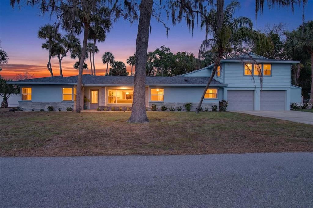 a front view of a house with a yard and tree s