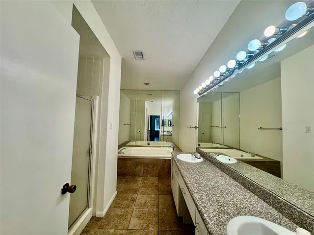 a en suite bathroom with a granite countertop sink and a mirror