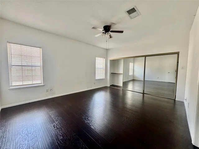 a view of empty room with wooden floor and fan