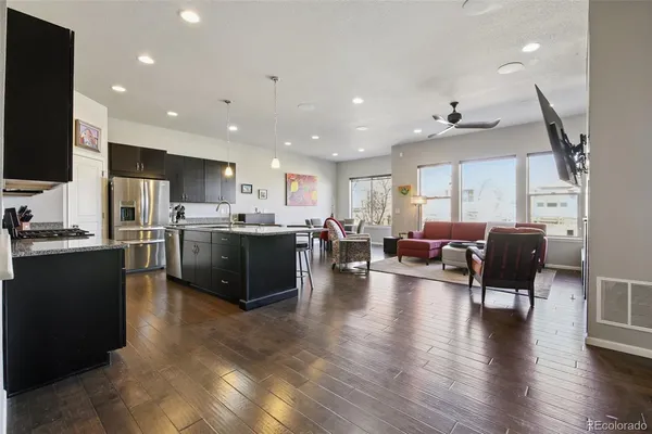 a living room with stainless steel appliances furniture refrigerator and kitchen view