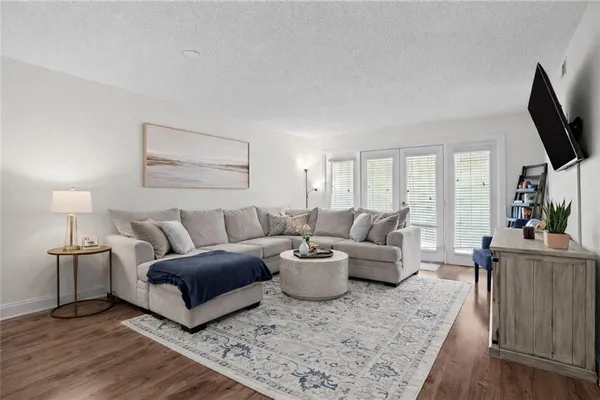 a living room with furniture a flat screen tv and a wooden floor
