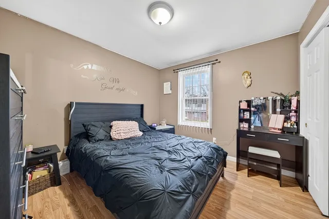a bedroom with a bed and dresser with wooden floor