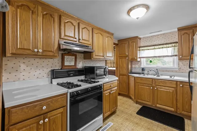 a kitchen with stainless steel appliances granite countertop a stove a sink and a microwave