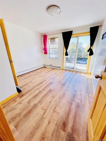 a view of an empty room with wooden floor and windows
