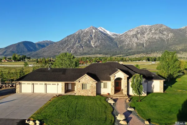 a front view of a house with a yard and mountain view in back