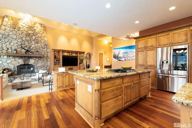 a large kitchen with stainless steel appliances granite countertop a lot of counter space and a wooden floor