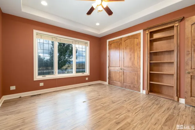 a view of empty room with wooden floor and fan
