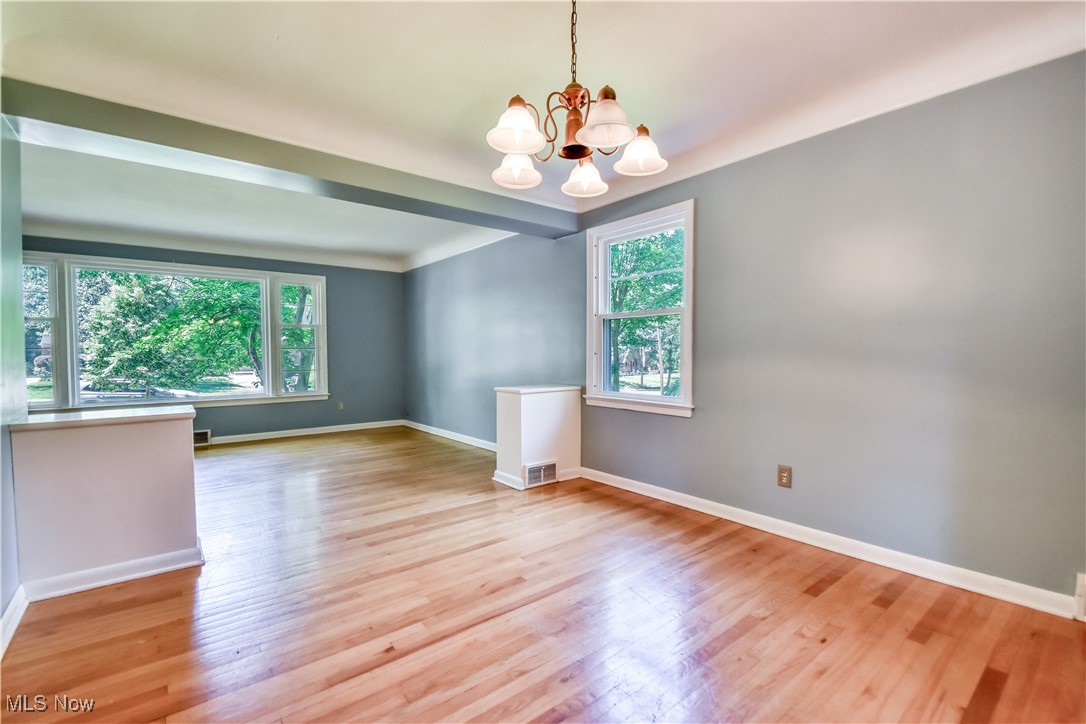2607 Ashurst Road University Heights, OH 44118 - Photo 16 of 39 Empty room featuring healthy amount of natural light, a chandelier, and wood finished floors