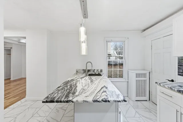 a kitchen with granite countertop a refrigerator oven a sink and white cabinets