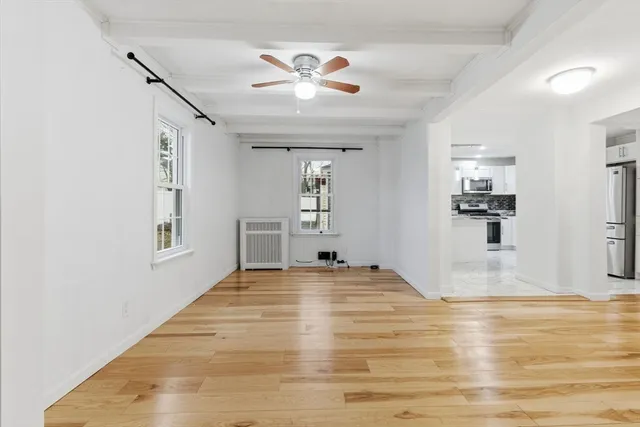a view of an empty room with kitchen and window