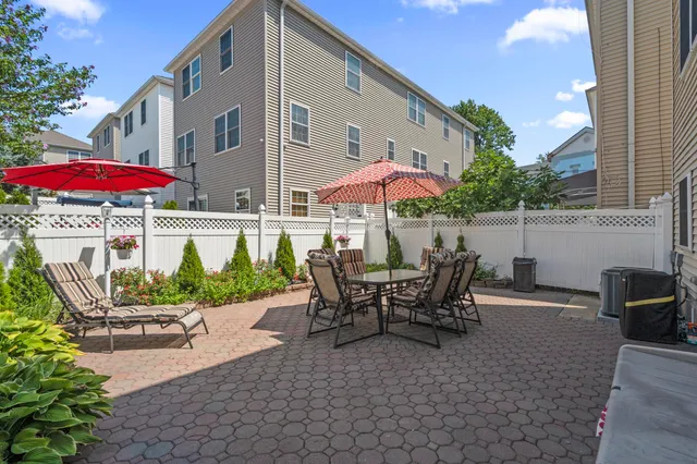 a view of a patio with couches table and chairs under an umbrella with a fire pit