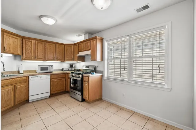 a kitchen with stainless steel appliances granite countertop a stove a sink and a microwave