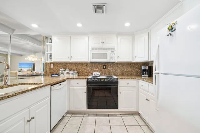 a kitchen with granite countertop white cabinets and white appliances