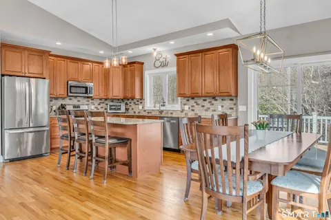 a kitchen with stainless steel appliances a dining table chairs sink and wooden floor