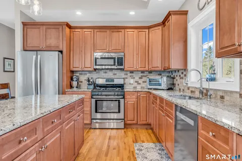 a kitchen with stainless steel appliances granite countertop a stove a sink dishwasher a refrigerator and a microwave