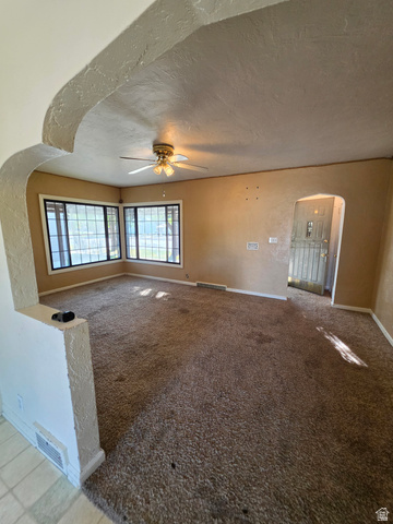 226 North State Street Preston, ID 83263 - Photo 7 of 18 Arched entryway leading to a carpeted room with multiple windows, a ceiling fan, and a light-colored wall finish