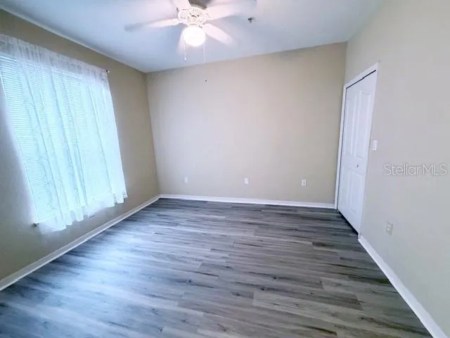 a view of an empty room with wooden floor and a window