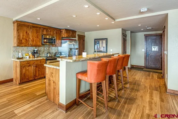 a dining hall with stainless steel appliances granite countertop a stove and a wooden floors