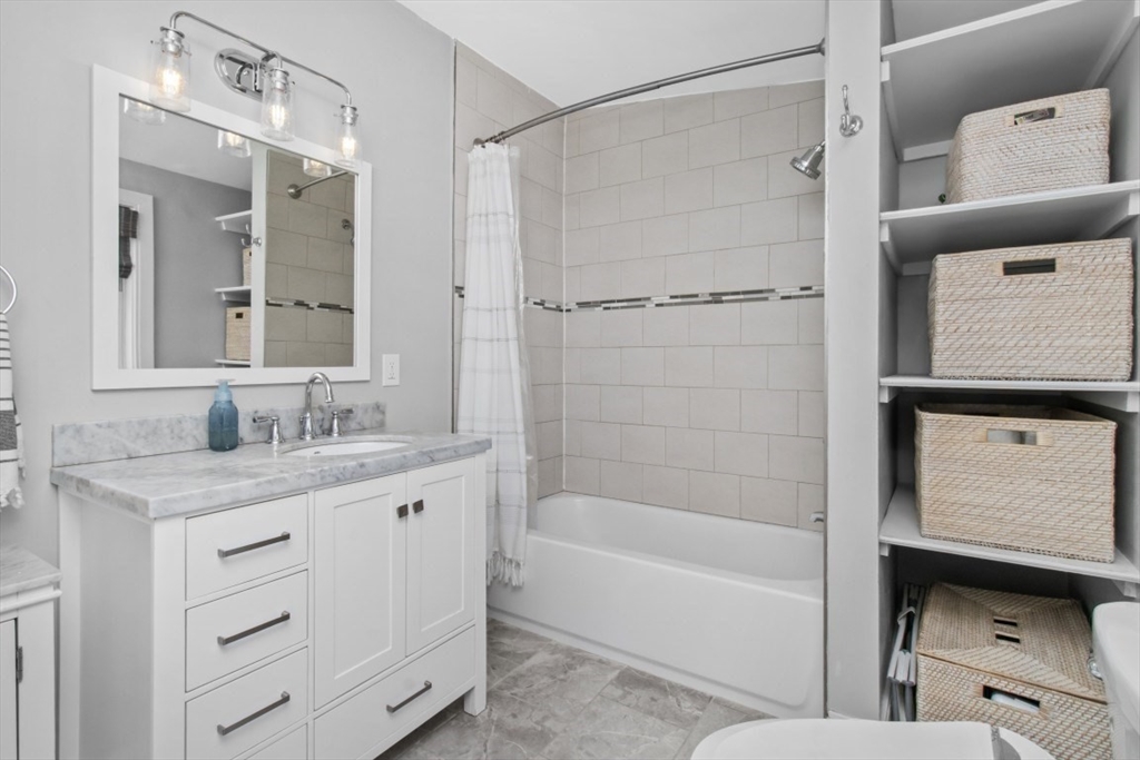 16 Port Norfolk Street, Unit 2 Boston, MA 02122 - Photo 9 of 20 a bathroom with a granite countertop sink a mirror and a bathtub