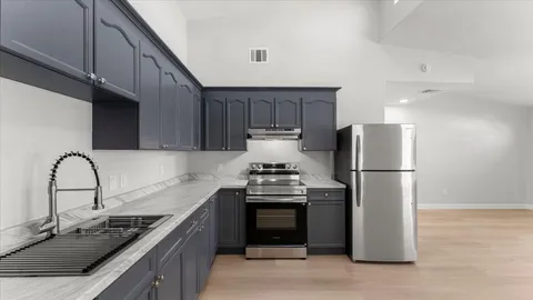 a kitchen with stainless steel appliances granite countertop a stove a refrigerator and a sink
