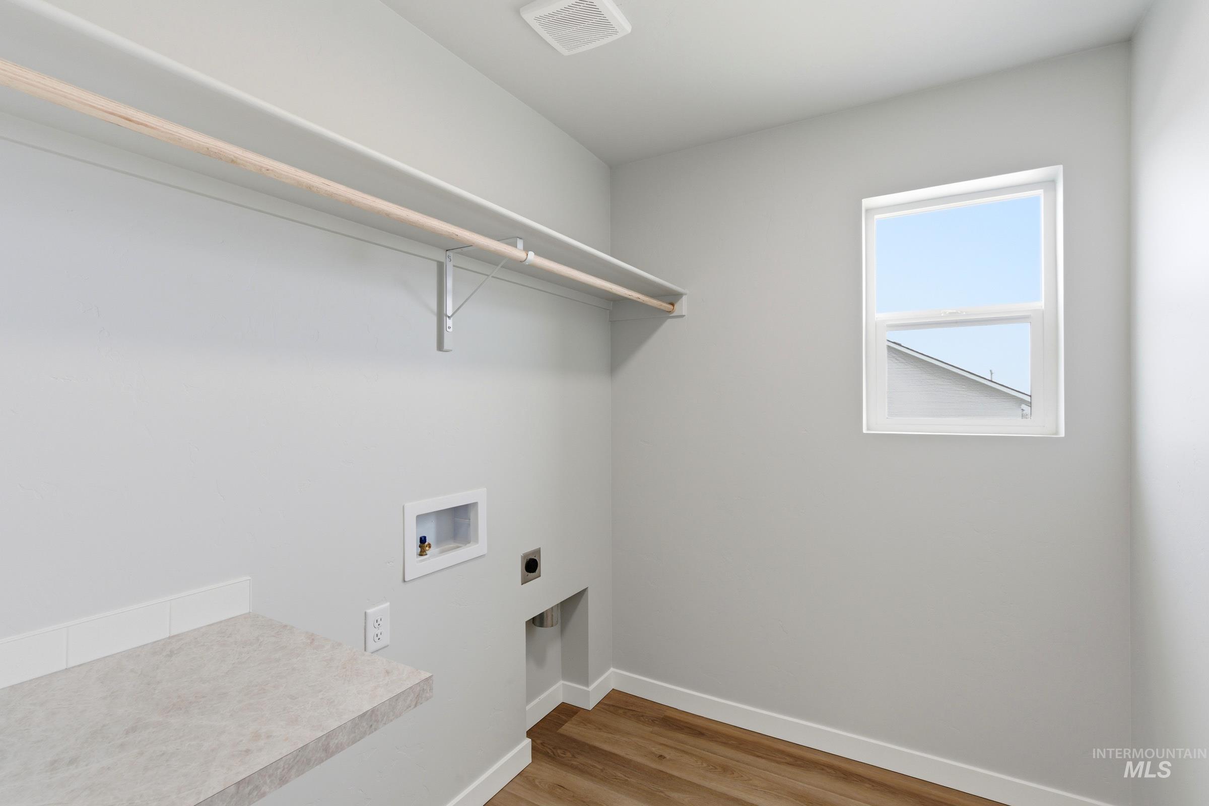 16558 Dunning Way Caldwell, ID 83607 - Photo 33 of 35 Laundry area featuring wood-finish flooring, a window, built-in shelving, a hanging rod, and a countertop with backsplash