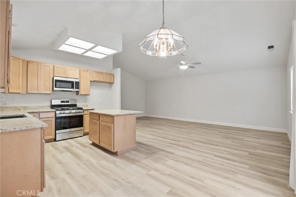 1165 Fig Street Corning, CA 96021 - Photo 15 of 46 a kitchen with stainless steel appliances granite countertop a stove top oven a sink dishwasher and white cabinets with wooden floor