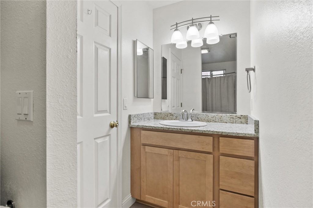 1165 Fig Street Corning, CA 96021 - Photo 23 of 46 a bathroom with a granite countertop sink a mirror and a vanity