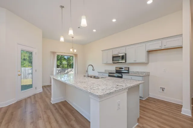 a kitchen with stainless steel appliances granite countertop a sink dishwasher and a stove with wooden floor