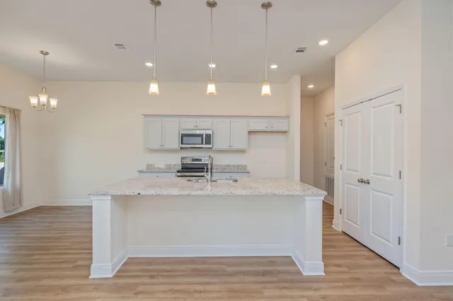 a view of kitchen with stainless steel appliances granite countertop cabinets and wooden floor