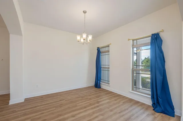 an empty room with windows and chandelier fan