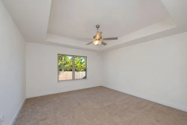an empty room with windows and ceiling fan
