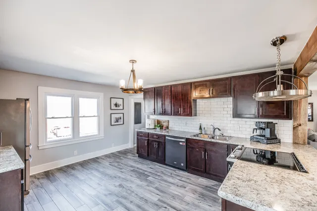a kitchen with stainless steel appliances granite countertop a sink a stove and a wooden floors