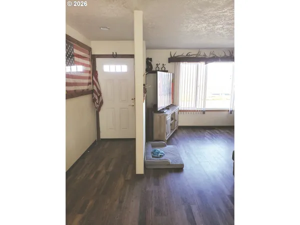 a view of empty room with wooden floor and window