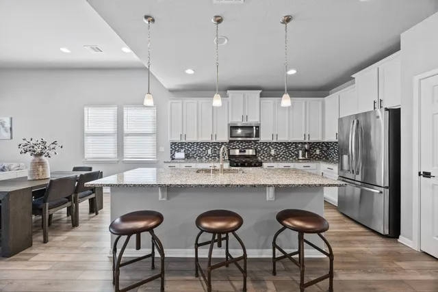 a kitchen with stainless steel appliances granite countertop a table chairs sink refrigerator and cabinets