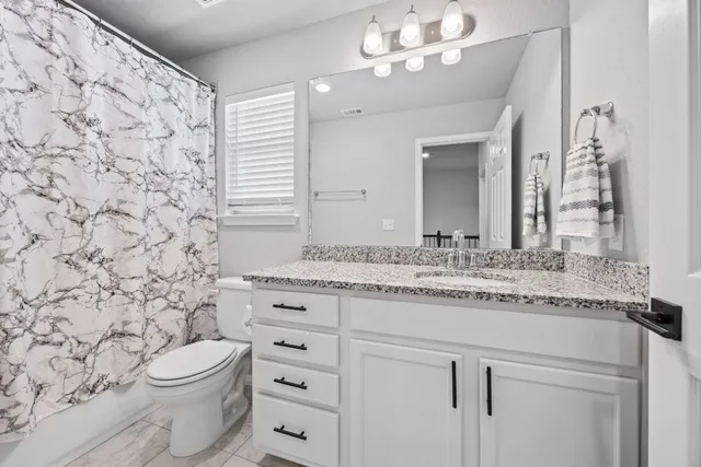 a bathroom with a granite countertop toilet sink and mirror